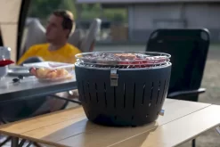 LotusGrill XL Hybrid Houtskoolbarbecue - Rood -Buiten koken Winkel lotusgrill in gebruik met toppy shirtje 2